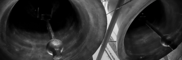 A close up of the underside of church bells in greyscale
