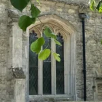 St James's Church side view through the overhanging leaves of a tree